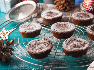 Chocolate chokecherry muffins with icing sugar. Winter christmas sweet food treat on dark green background