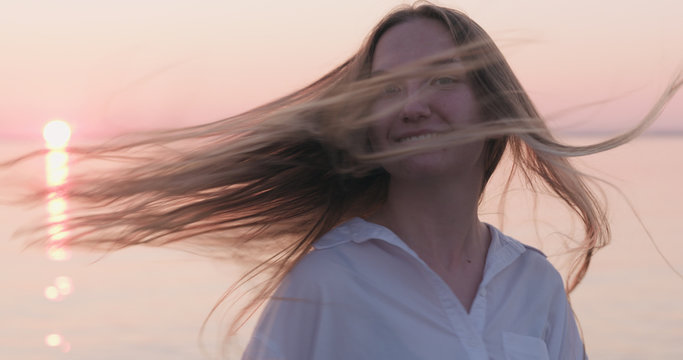 teenage girl turns around and having fun with her hair on a beach at sunset