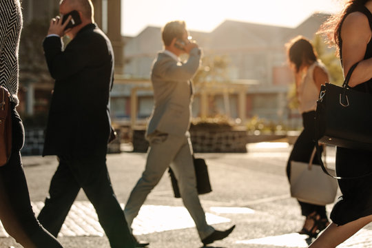 Business people busy using mobile phone while walking on street