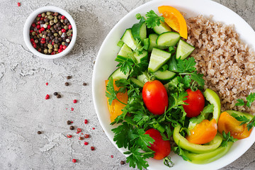 Diet menu. Healthy vegetarian salad of fresh vegetables - tomatoes, cucumber, sweet peppers and porridge on bowl. Vegan food. Flat lay. Top view