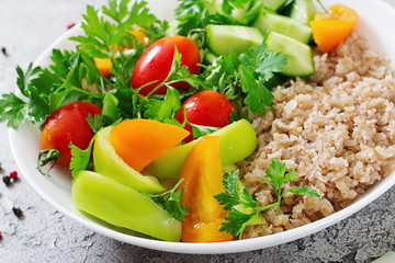 Diet menu. Healthy vegetarian salad of fresh vegetables - tomatoes, cucumber, sweet peppers and porridge on bowl. Vegan food.