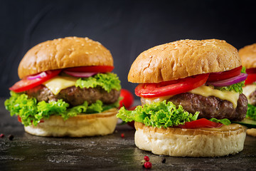 Hamburger with beef meat burger and fresh vegetables on dark background. Tasty food.
