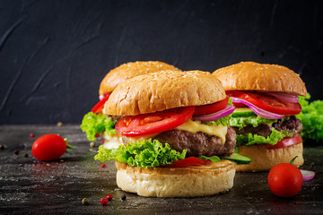 Hamburger with beef meat burger and fresh vegetables on dark background. Tasty food.