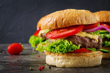 Hamburger with beef meat burger and fresh vegetables on dark background. Tasty food.
