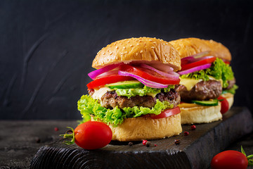 Hamburger with beef meat burger and fresh vegetables on dark background. Tasty food.
