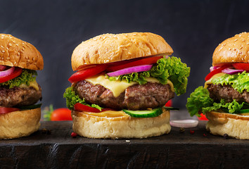 Hamburger with beef meat burger and fresh vegetables on dark background. Tasty food.