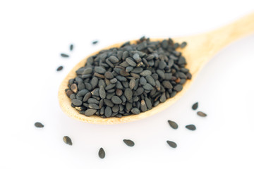 Heap of black sesame on wooden spoon on white background.