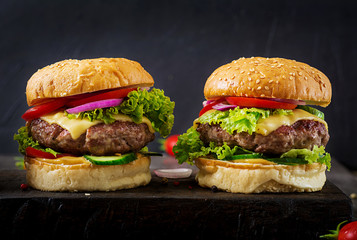 Hamburger with beef meat burger and fresh vegetables on dark background. Tasty food.