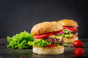 Hamburger with beef meat burger and fresh vegetables on dark background. Tasty food.