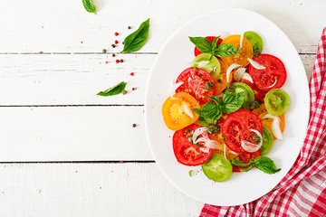 Colored tomato salad with onion and basil pesto. Vegan food. Top view. Flat lay