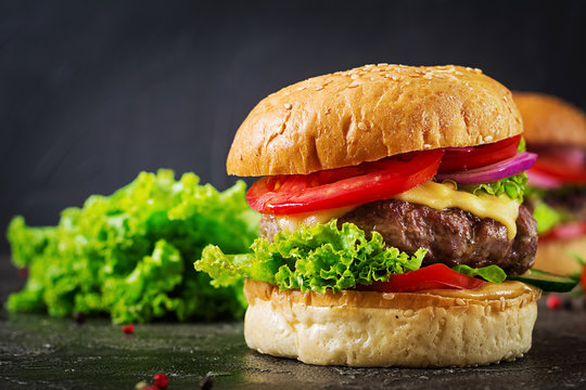 Hamburger with beef meat burger and fresh vegetables on dark background. Tasty food.