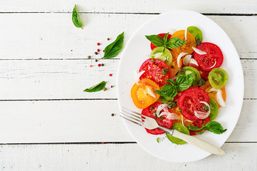 Colored tomato salad with onion and basil pesto. Vegan food. Top view. Flat lay