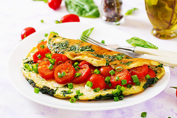 Fototapeta na wymiar Omelette with tomatoes, spinach and green onion on white plate. Frittata - italian omelet.