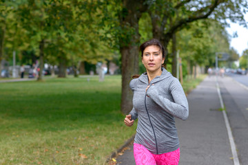 Fit adult woman running on concrete sidewalk