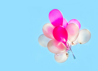 Different color pink and white bachelorette or birthday party helium gas filled balloons against blue sky outdoors on sunny day.