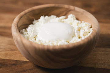 cottage cheese with sour cream in wood bowl on table