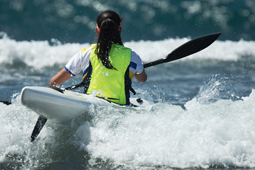 Paddlers race their ocean kayak surf skis through breaking waves