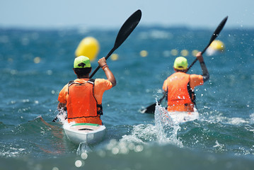 Paddlers race their ocean kayak surf skis through breaking waves