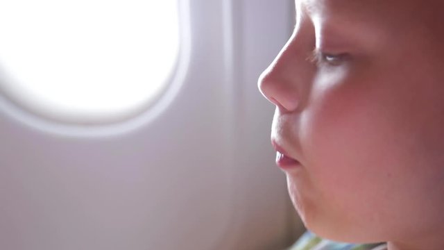 Closeup View Of Cute Little Kid Chewing Gum And Blowing Bubbles While Having Flight By Airplane. Real Time Full Hd Video Footage. 