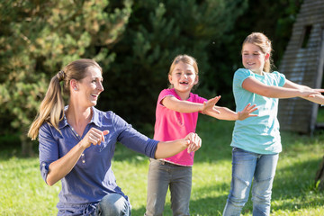 Happy mother with children daughters doing dance exercise outdoors
