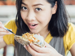 Woman eats Thai style fresh oyster with garlic.