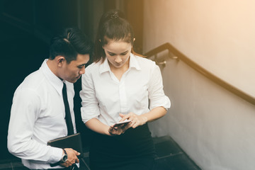 Two people looking smartphone and analyzing the stock graphs in the morning before going to work.