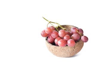 red grapes inside dry coconut shells isolated on white background. selective focus.