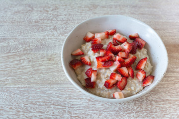Rolled  organic porridge with strawberries in murble bowl on wood table healthy breackfast
