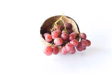 red grapes inside dry coconut shells isolated on white background. selective focus.