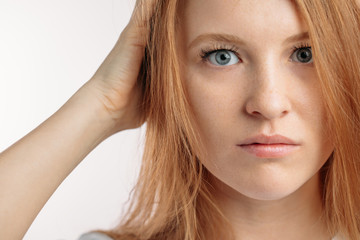serious redhair model with blue eyes.holding her head. close up cropped photo.a nice girl is...