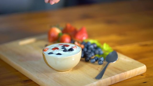 Close up, Put the blueberries and strawberries into the yogurt cup slowly.