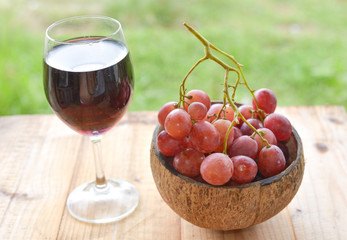 red grapes and a glass of wine on wooden table. selective focus.