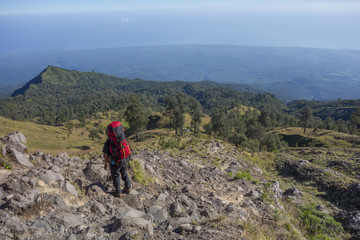 Fototapeta na wymiar Unidentified mountain guide with trekking pole looks on the way to Rinjani Mountain in Lombok, Indonesia.