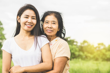 Obraz premium happy family Asian mother and daughter hugging each others in a park smiling at a camera 