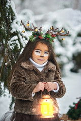 Fairy tale girl. Portrait a little girl in a deer dress with a painted face in the winter forest....