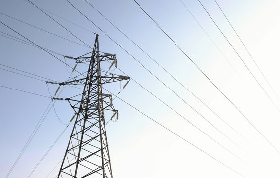 High-voltage tower, transmission line in sky background.