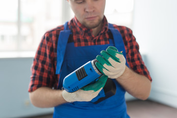 Close up of serious handsome male builder with screwdriver wearing white helmet.