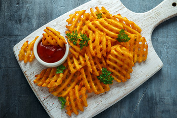 Crispy Potato Waffles Fries with Ketchup on white wooden board © grinchh