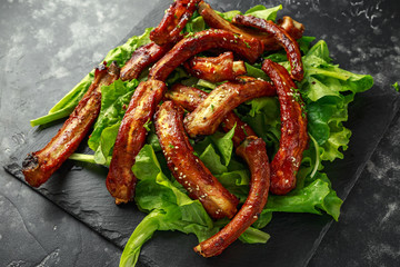 Roasted barbecue hot pork ribs served on stone board with vegetable