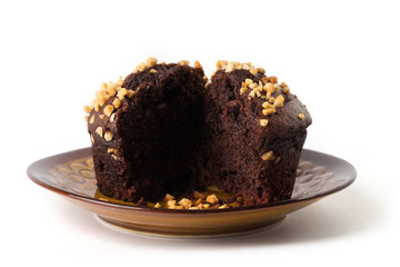 Cut in half chocolate muffin with a jam heart on a brown plate, isolated on white background