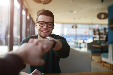 Cheerful young male colleagues IT developers high fiving during morning motivation meeting...