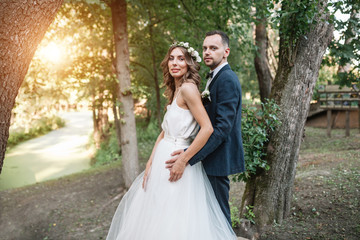 Fototapeta premium Bride and groom at wedding Day walking Outdoors on summer nature. Bridal couple, Happy Newlywed woman and man embracing in green park. Loving wedding couple outdoor. Bride and groom