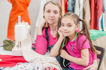portrait of a mother with her daughter in the workplace seamstresses, near the sewing machine