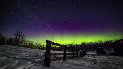Winter time lapse of the northern lights and stars over a wooden fence and grain bin on an abandoned farm in Alberta, Canada - Powered by Adobe