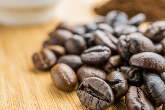 close-up coffee beans with cup on wooden rustic board