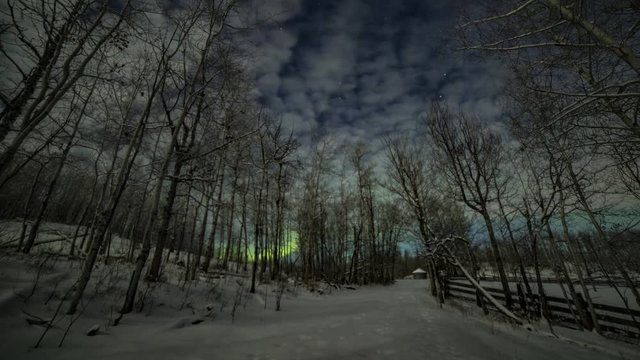 Winter time lapse of stars, clouds, moonlight and northern lights over a snowy road at an abandoned farm in rural Alberta, Canada
