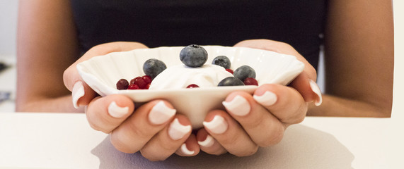 A cup of coffee in the girl's hand, chocolate, berries. Breakfast.