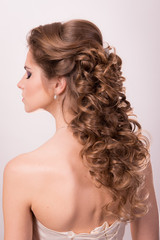 Wedding hairstyle on the head of a brown-haired woman in the back view on a white background close-up.