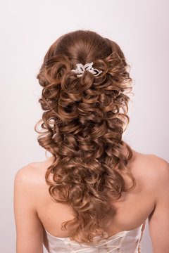 Wedding hairstyle on the head of a brown-haired woman in the back view on a white background close-up.