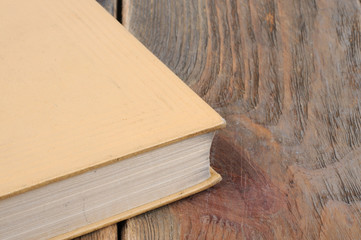 A book in yellow binding on a wooden background. Front view.